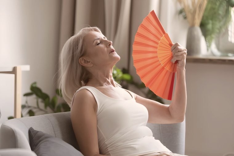 Woman cooling herself with a fan